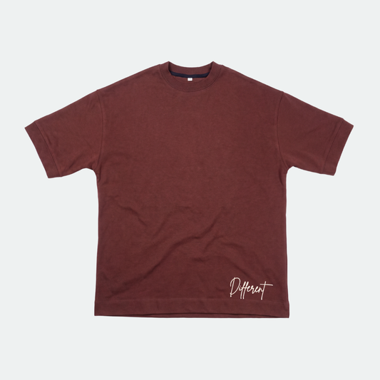 A dark reddish-brown short-sleeve t-shirt with a white script logo reading 'Different' on the bottom right, displayed flat against a light gray background.